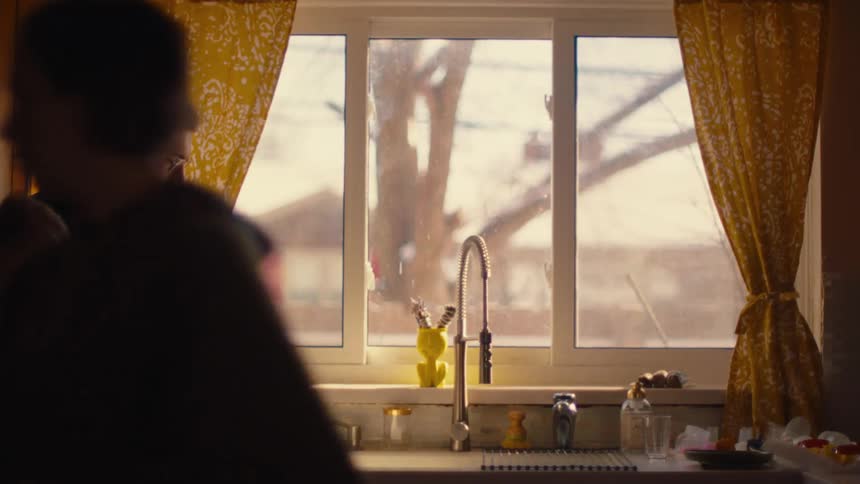 Mother hands daughter a roller then leaves her sitting on the kitchen counter next to her father and baby sibling