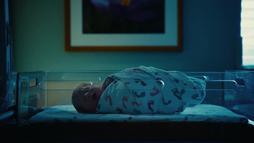 A little baby wrapped in a blanket is yawning
