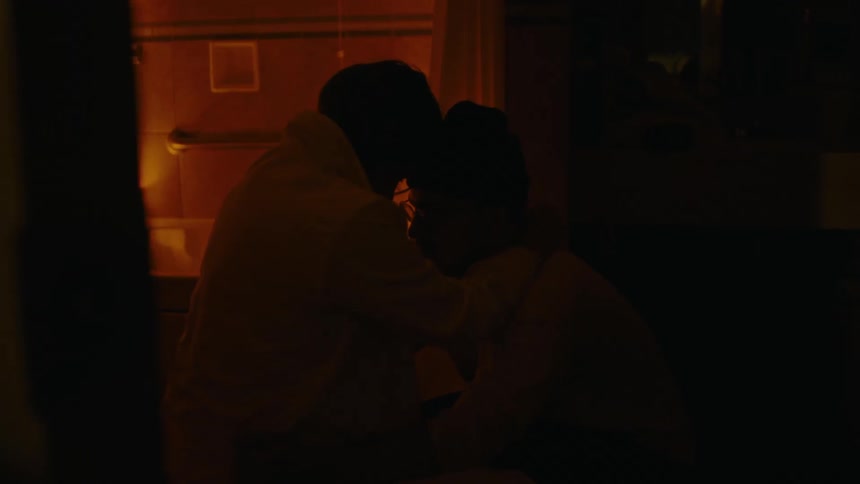 Man and woman embracing in a bathroom with a bathtub with lit candles