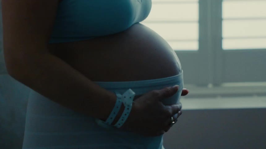 Pregnant woman running her hands over her belly massaging it