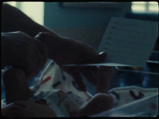 A tender moment of a newborns tiny feed being printed on a card in a softly lit room