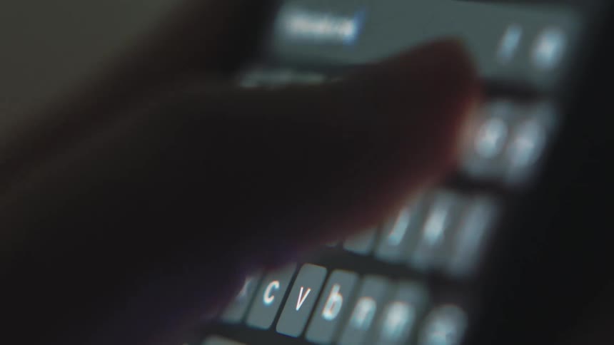 Person types on smartphone in dark area