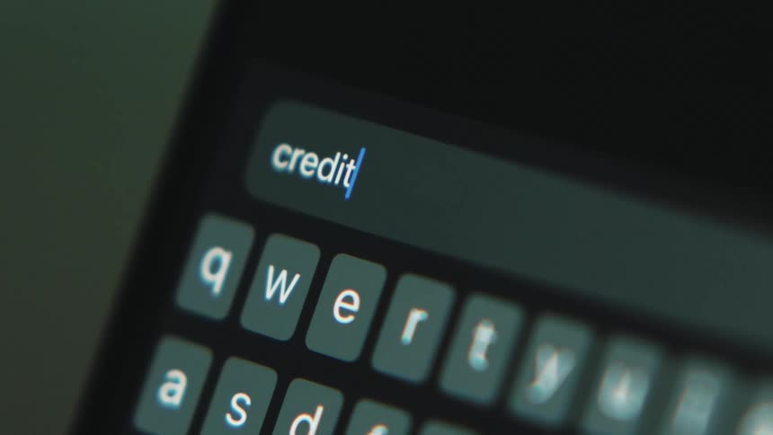 White letters are on a small keyboard as someone types credit score