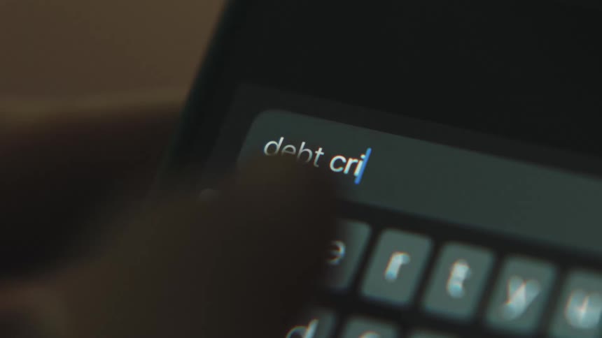 Close up of hand texting debt crisis on smartphone