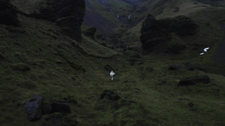 Person walking in a narrow valley with grassy and rocky slopes