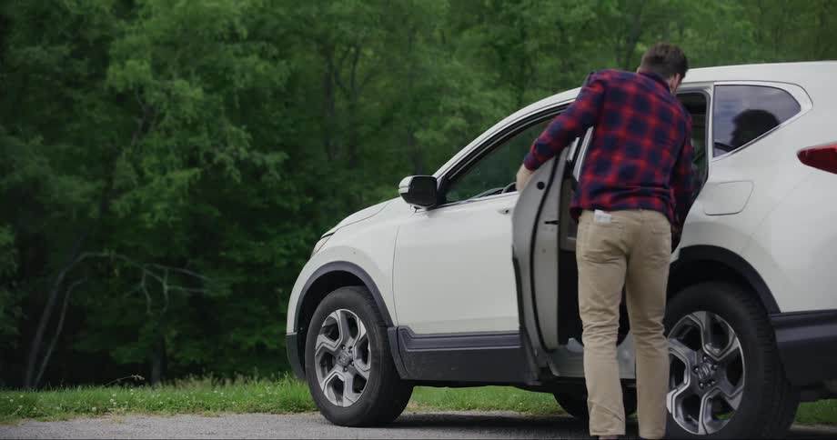 Man parks his car and then runs toward the forest with his dog