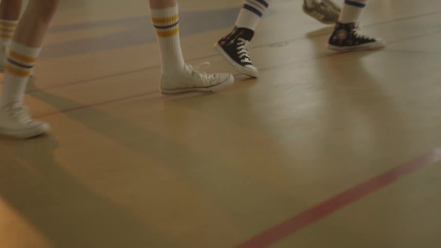 Several legs sees some children with big socks and they are going left and right on a smooth floor court
