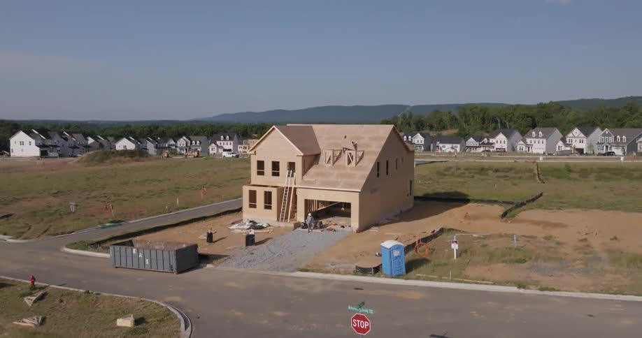 Two construction workers build a twostory house in a suburb