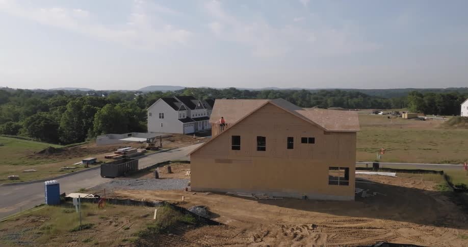 A house under construction with a construction worker on the roof