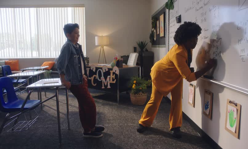 A female teacher gives a student a high five after she shows him how to work a problem on a whiteboard