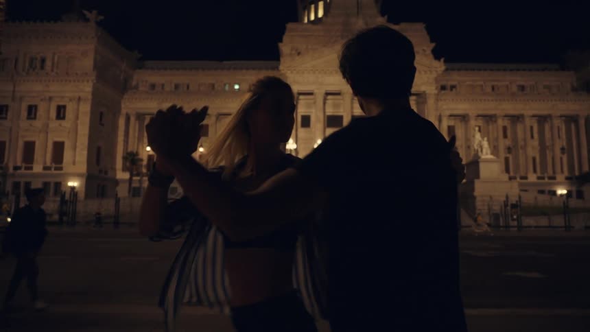 Silhouette of a young couple dancing in the city at night