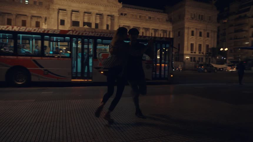 Two people dance outside in the city