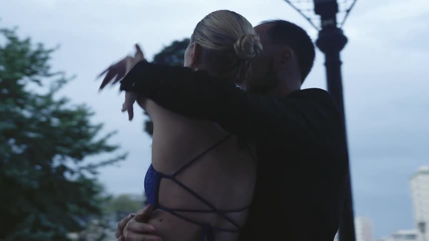 Man in a suit dancing with a woman in a blue dress in a performance