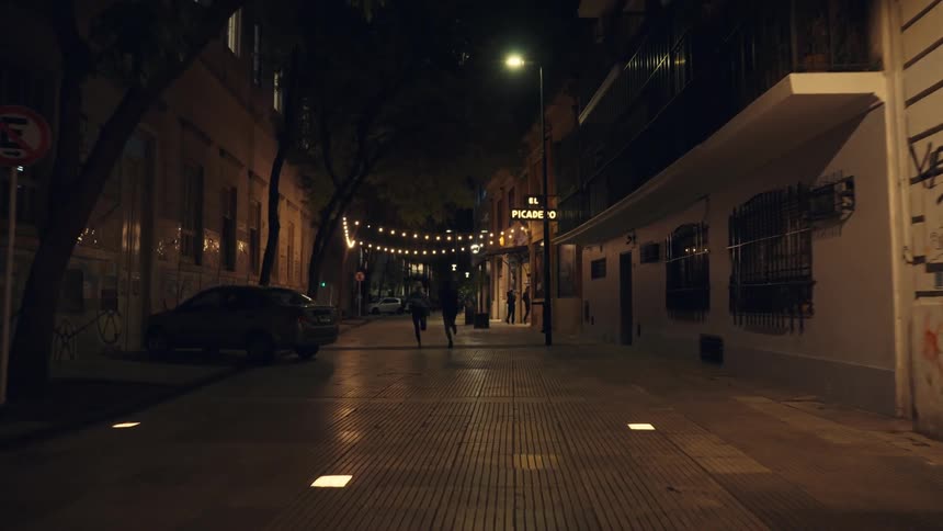 Silhouette of two people running in a lowlit alley at night