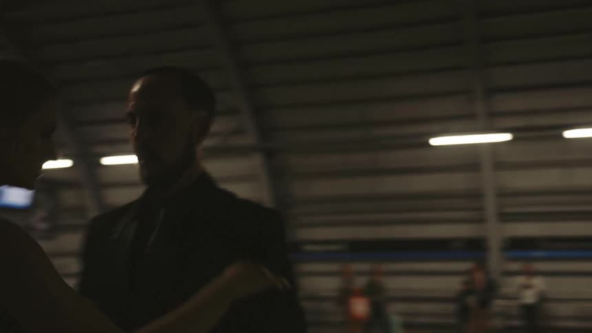 A couple dances in a dimly lit train station