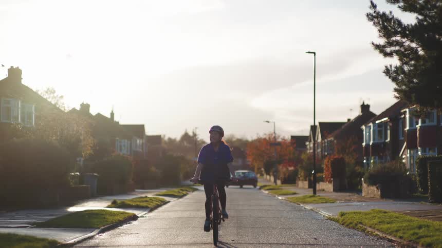 Woman riding a bicycle down the street in a residential neighborhood