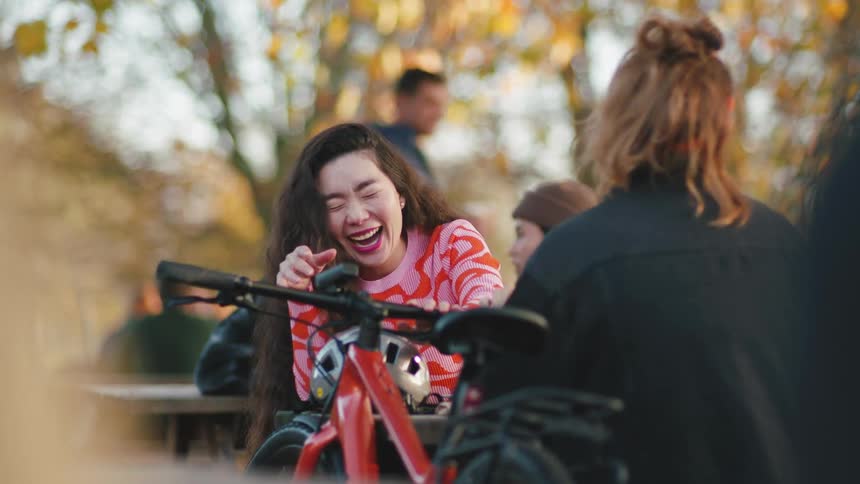 Friends talk and laugh on a park surrounded by autumn folliage