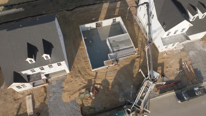 Aerial view of a concrete pump filling the foundations of a house being constructed in the neighborhood