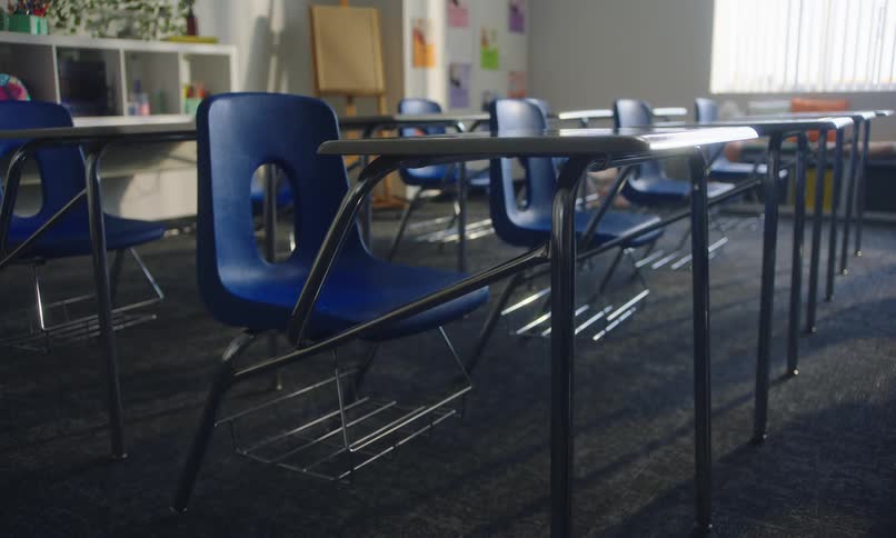 Vacant students desks lined up in a row in an empty classroom
