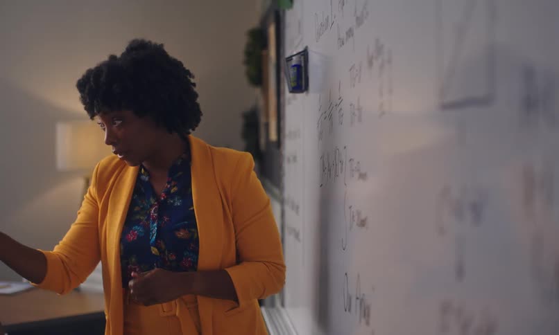 Teacher writing on a whiteboard inside the classroom and explaining