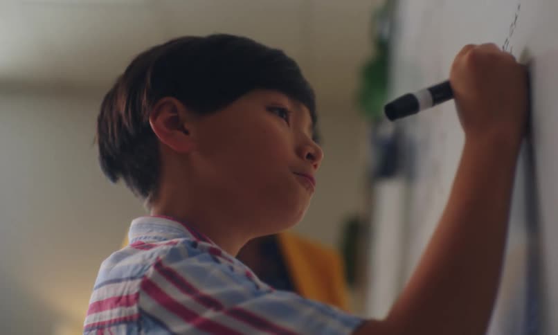 A student solves math problems on a whiteboard at school