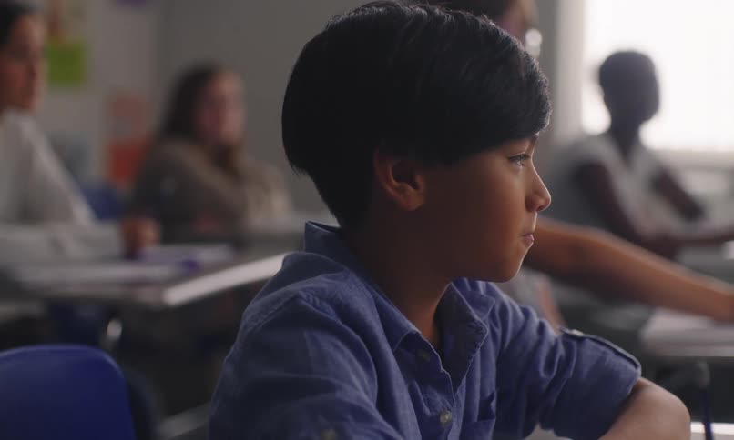 Portrait of a boy in a classroom with other students in the background