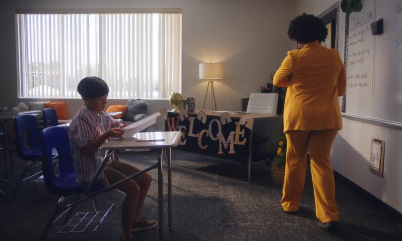 An adult explains an exam to a child in a classroom
