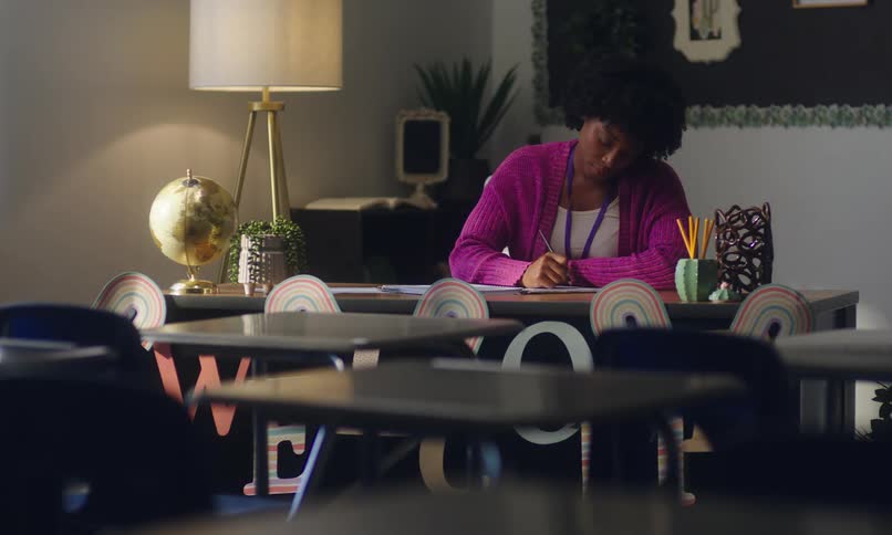 Teacher in a classroom sitting at her desk and writing