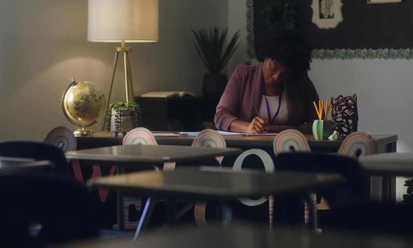 Teacher sitting at a desk in the classroom writing
