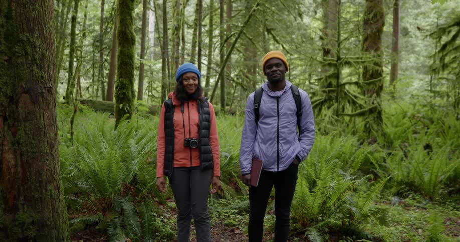 Two backpackers smile while posing in a forest together