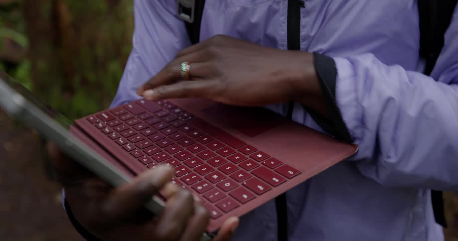 Closeup of a persons hands typing on a red laptop keyboard