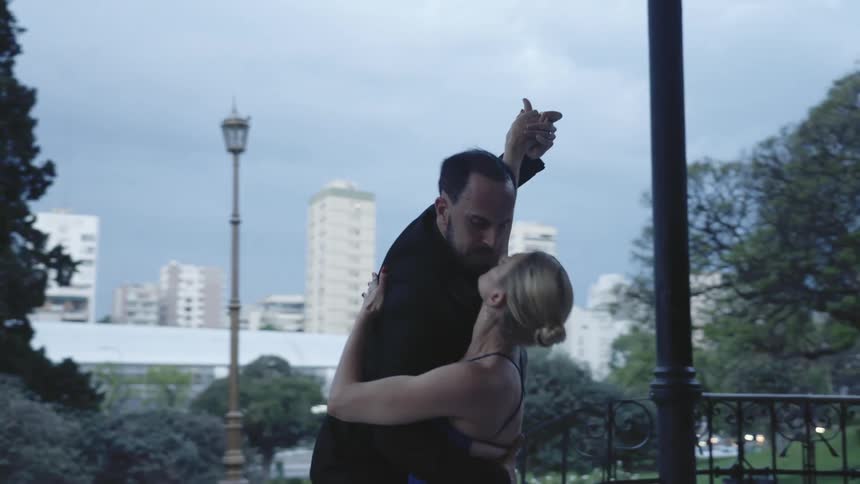 Two dancers perform an outdoor routine on a park in the city