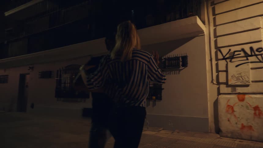 Man and woman dancing in an alley at night