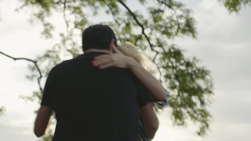 Man and woman dancing tango in an open space beneath a tree