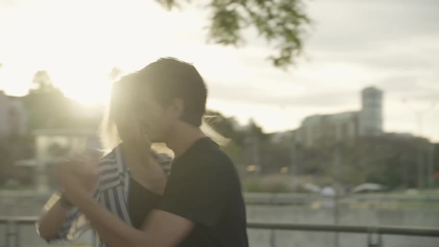 A couple dancing closely in a park during sunset
