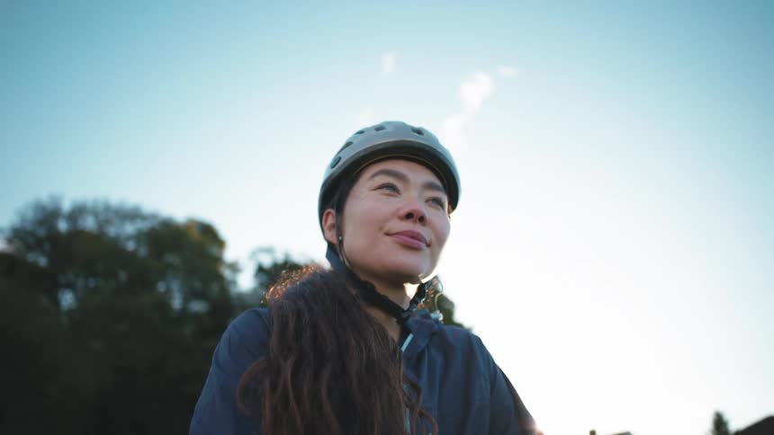 A young girl has a smile on her face and is wearing a helmet while sitting on a bicycle
