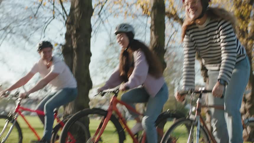 Three friends riding bicycles in a park at morning
