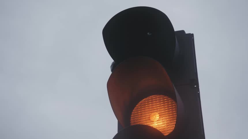 Close up of a traffic light turning on the orange and red lights