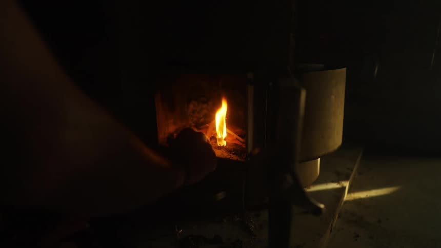 Persons hand lighting a fire in a small fireplace