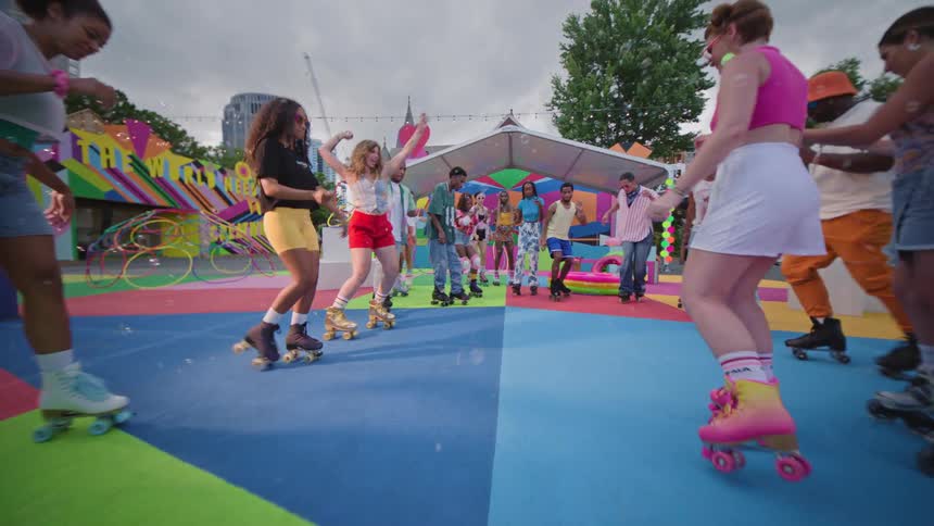 Group of men and women dancing together in a circle with roller skates in a colorful openair playground