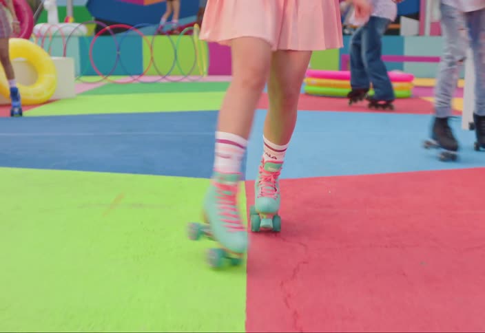 Woman in pink dress rollerblading on a colorful playground