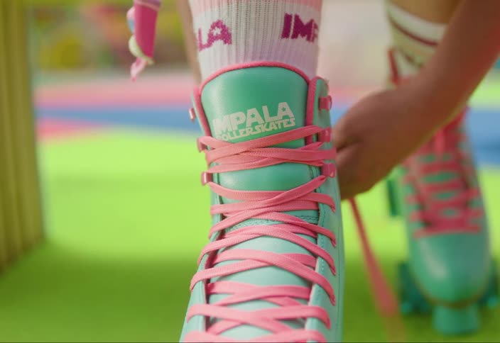 A person is tying a pink shoelace of a green roller