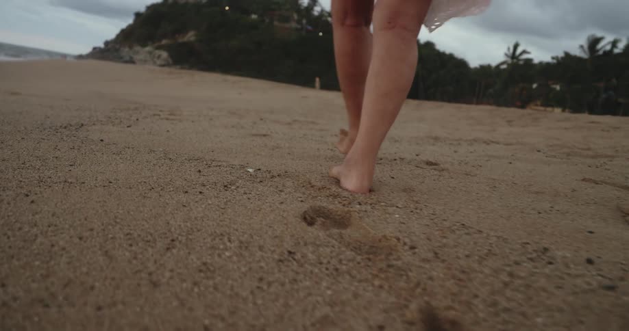 Feet of a person walking on the sand at the beach