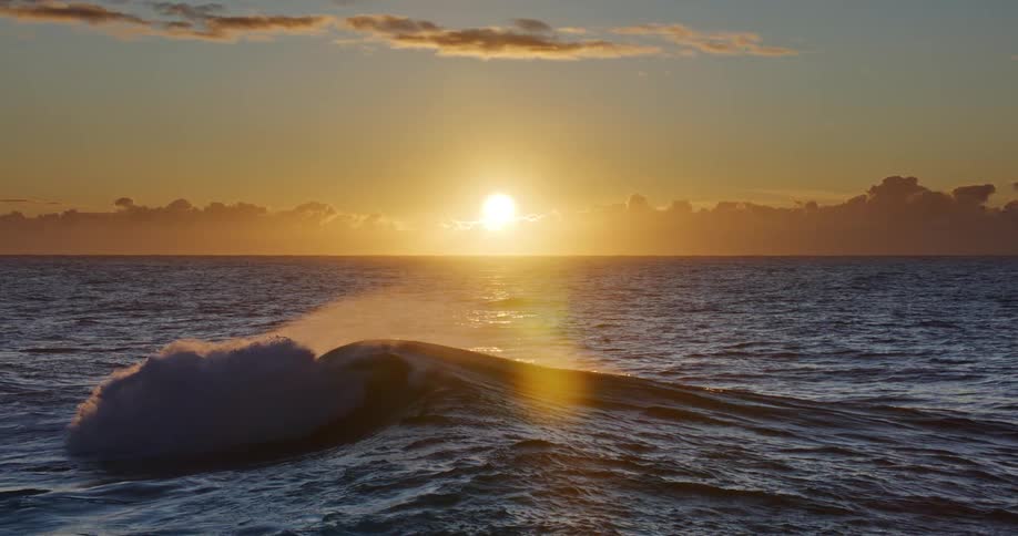 Landscape of small waves in the sea with the sunrise on the horizon