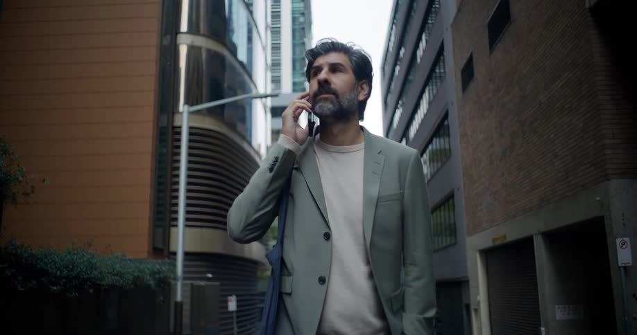 An older man walks through a city downtown while using a smartphone