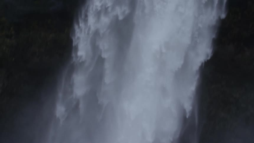 Waterfall splashes from the mountain into the lake below