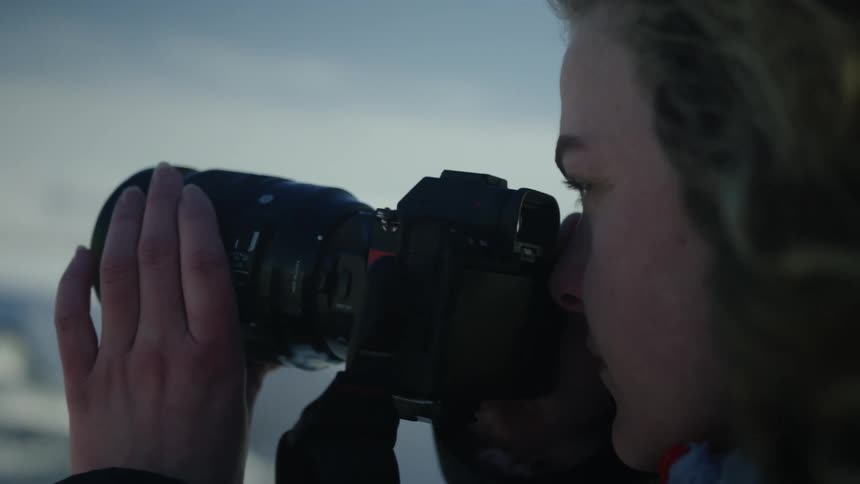 Side portrait of a woman with a professional camera getting ready in a natural setting