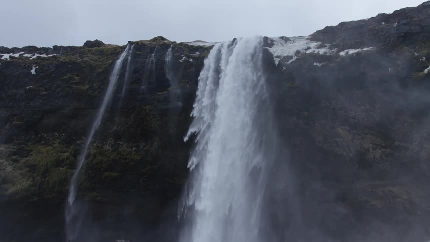 The waterfall pours off the cliff