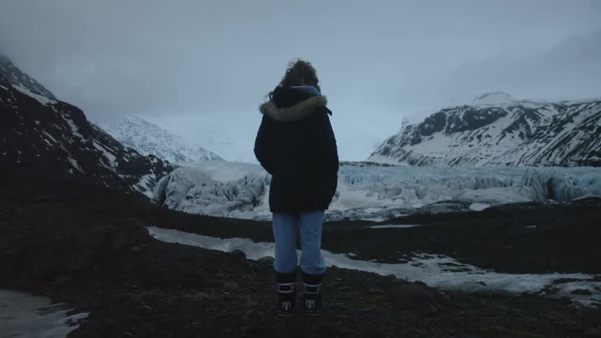 A woman standing on a glacier looking into the distance