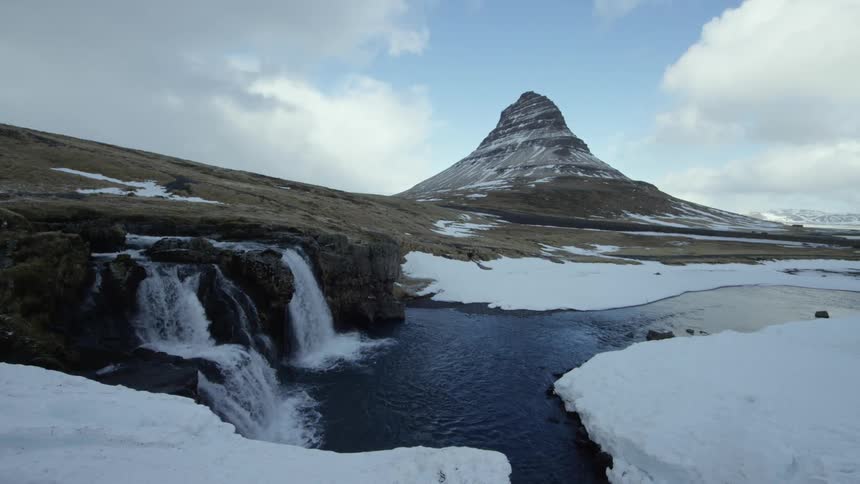A waterfall is near the mountain